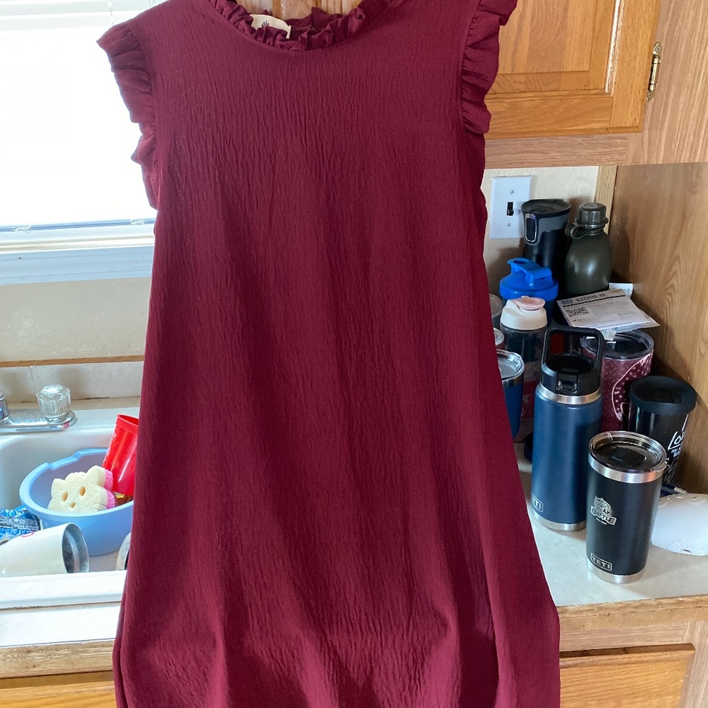 A boutique style dress maroon in color goes just passed the knees